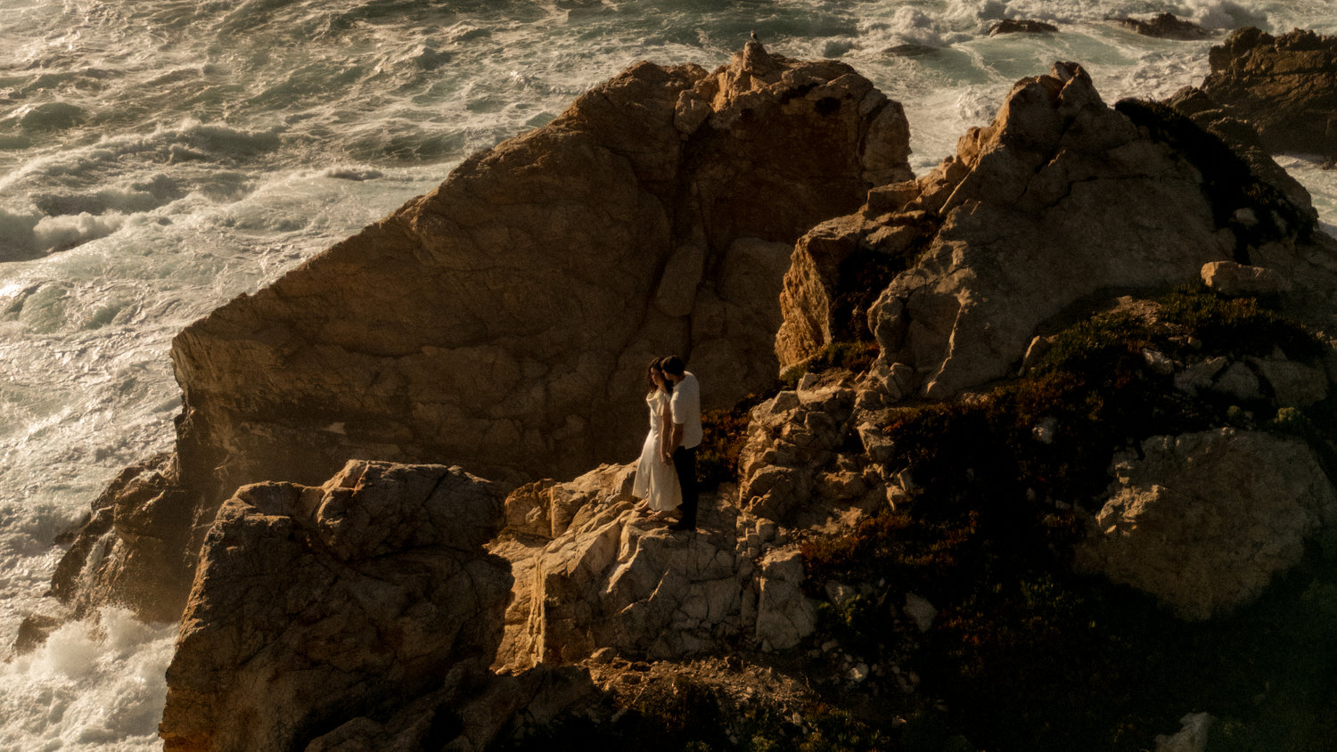 Couple sitting on rocky coast by the sea