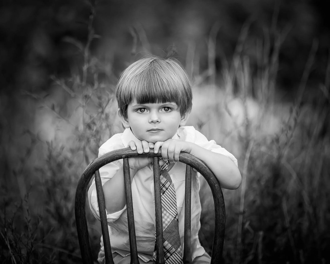 Timeless black and white headshot of a boy, captured in natural light with a sweet expression.