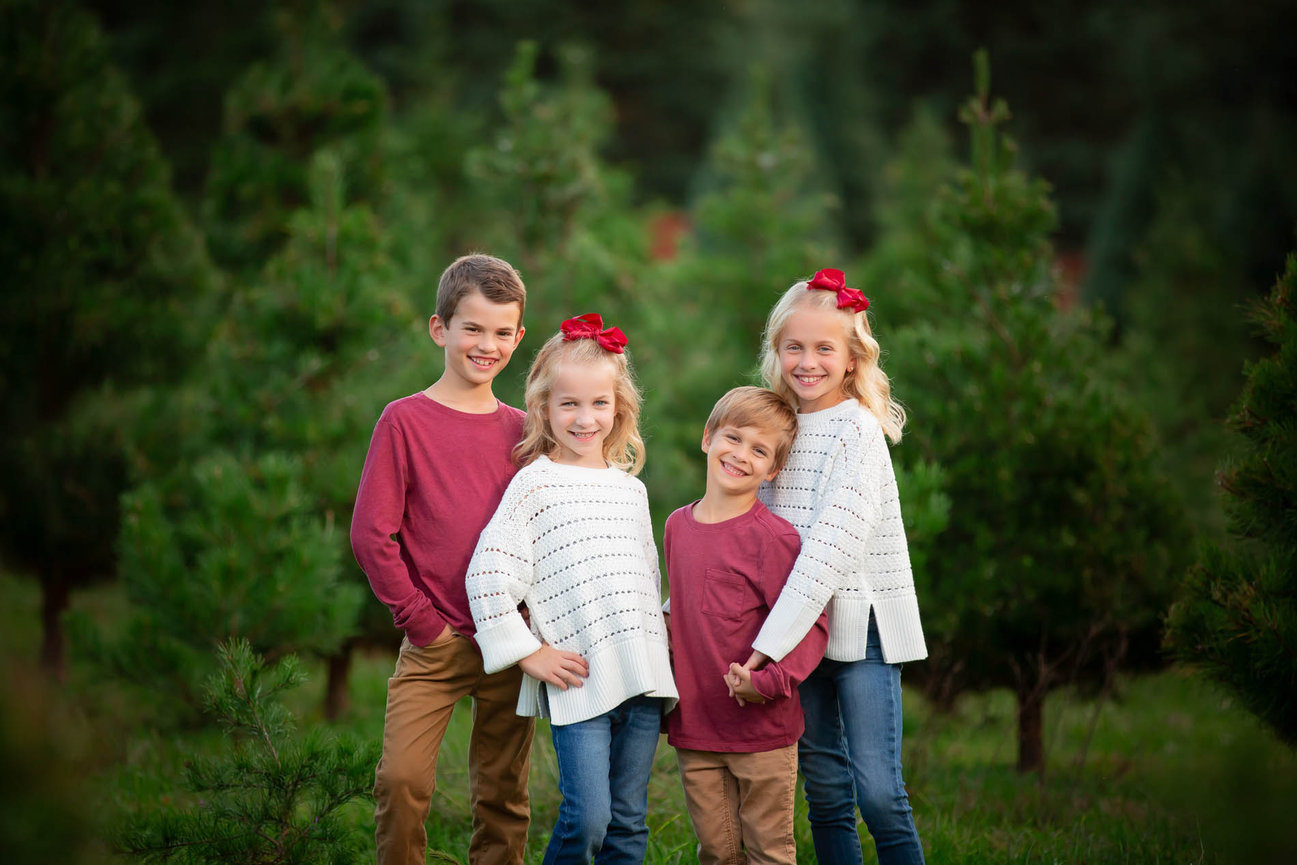 Four children smiling joyfully together in a family portrait session in Raleigh, NC.