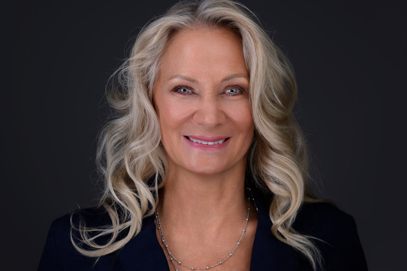 Professional headshot of smiling woman with wavy blonde hair wearing navy blazer, taken by DFW personal branding and headshot photographer