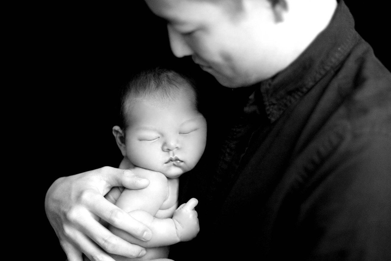 Black and white photo of a father holding his newborn baby