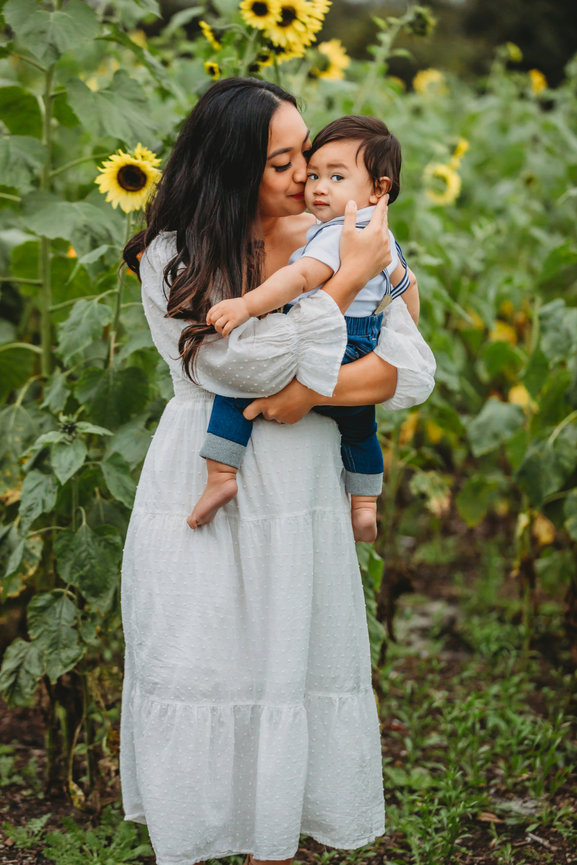Mom cuddling baby in sunflower field in Astatula, Florida.
