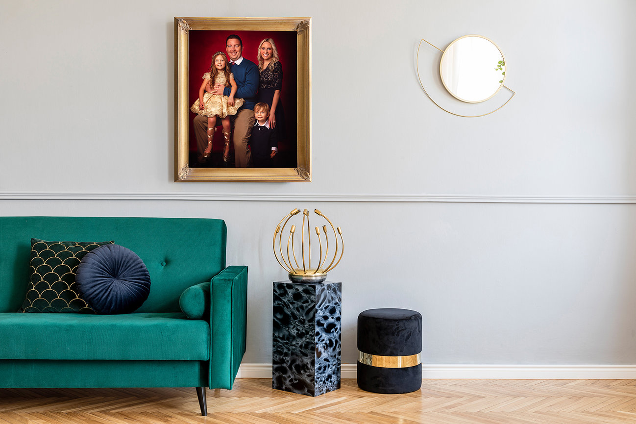 Sophisticated living room with a green sofa, family portrait, abstract decor, and parquet flooring.