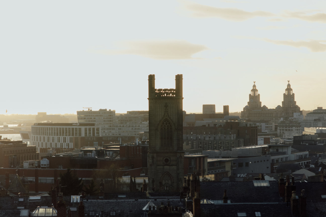 City skyline from Hope Street Hotel at sunset with historic and modern buildings, silhouetted against a bright sky.