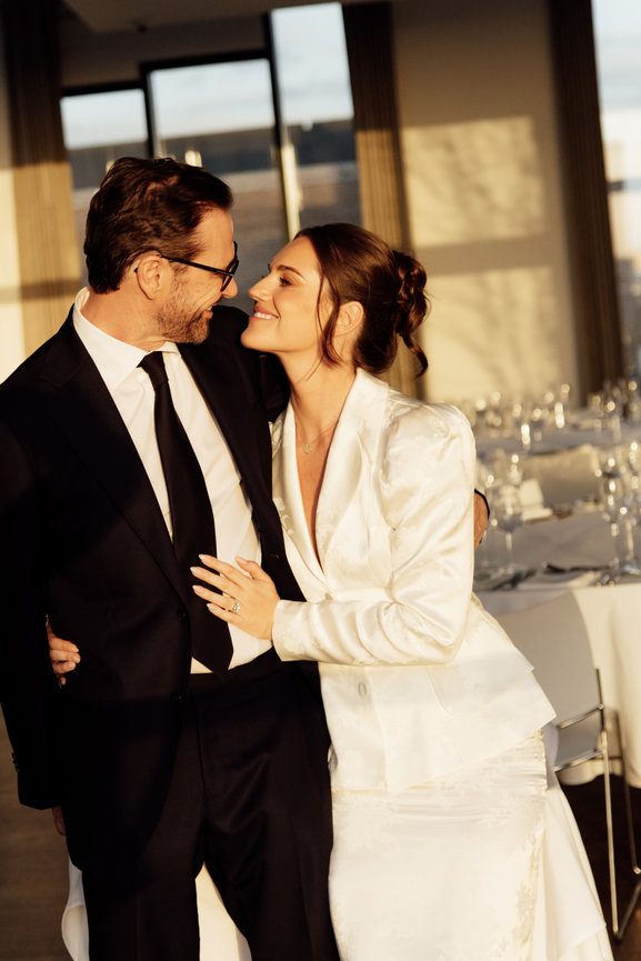 Relaxed editorial wedding photography of a bride leaning into her groom in a golden hour lit dining room with elegant table settings at Hope Street Hotel, Liverpool.