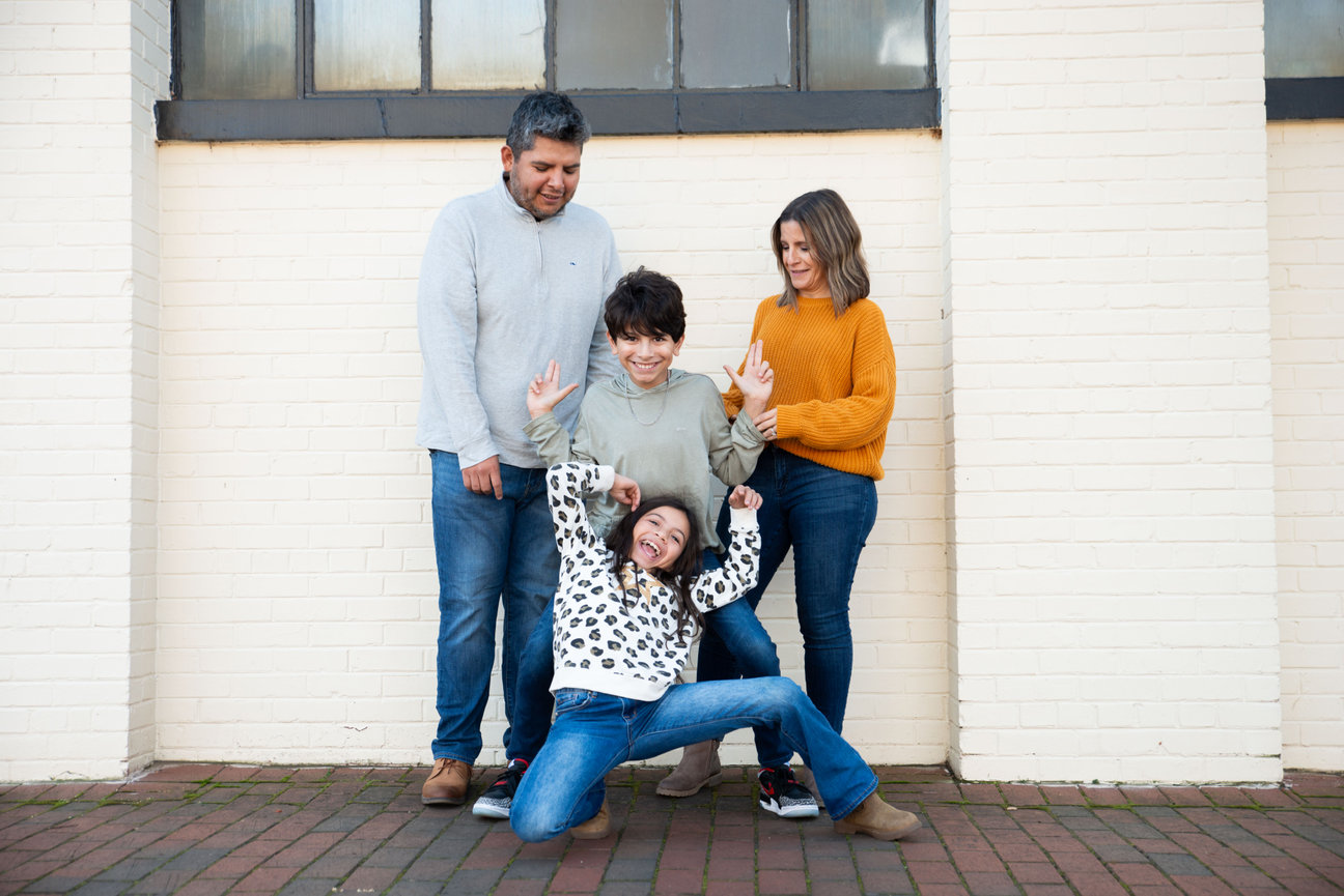 Family posing together in front of a white building.