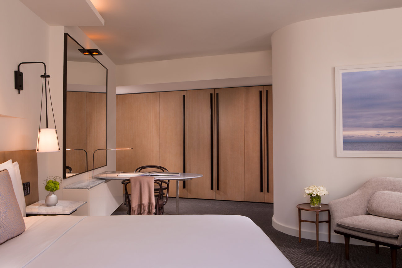 Guest room at The Conrad Hotel showcasing Beautiful Artwork large amounts of closet space and modern furniture.