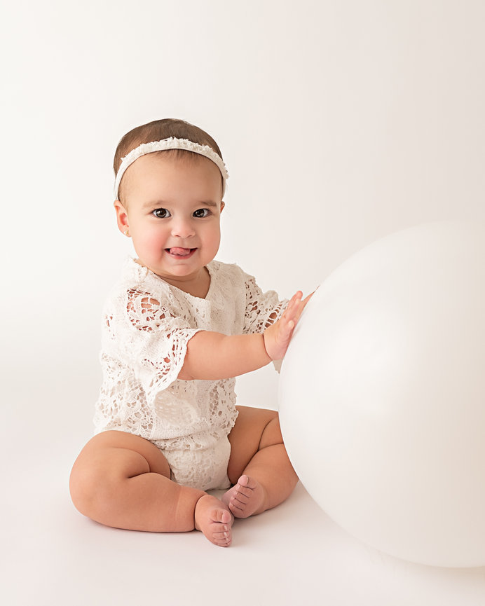 Sweet portrait taken in Colts Neck of baby laughing while playing with large white balloon