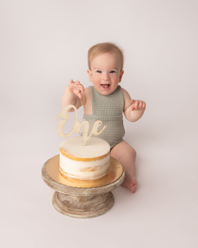 Clean portrait of baby sitting happily before diving into cake