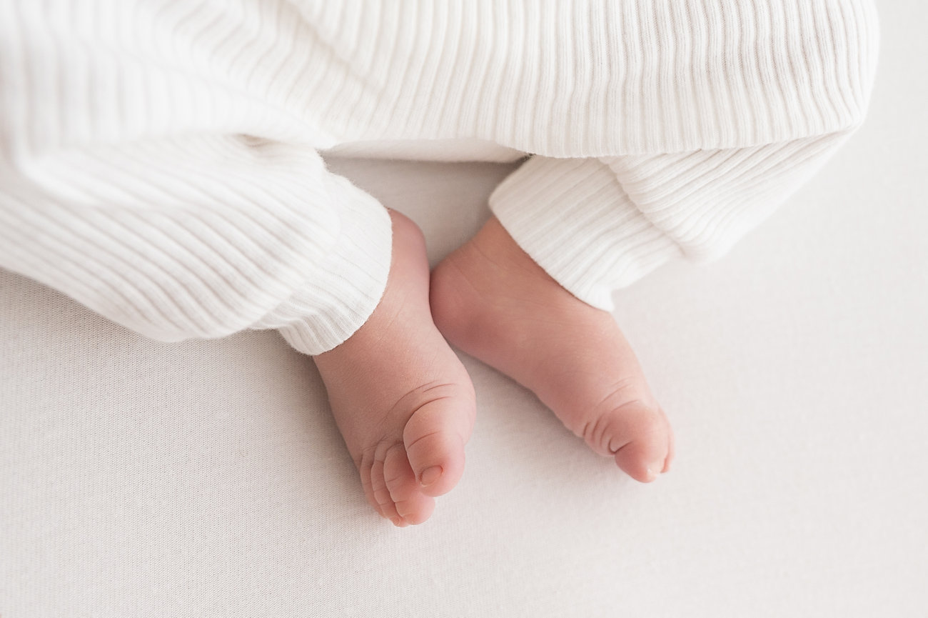 Baby’s feet peeking out from white onesie
