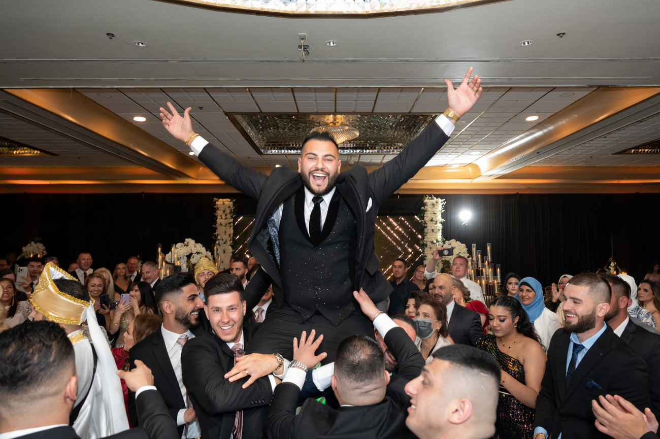 Groom being lifted high by wedding crowd during wedding reception