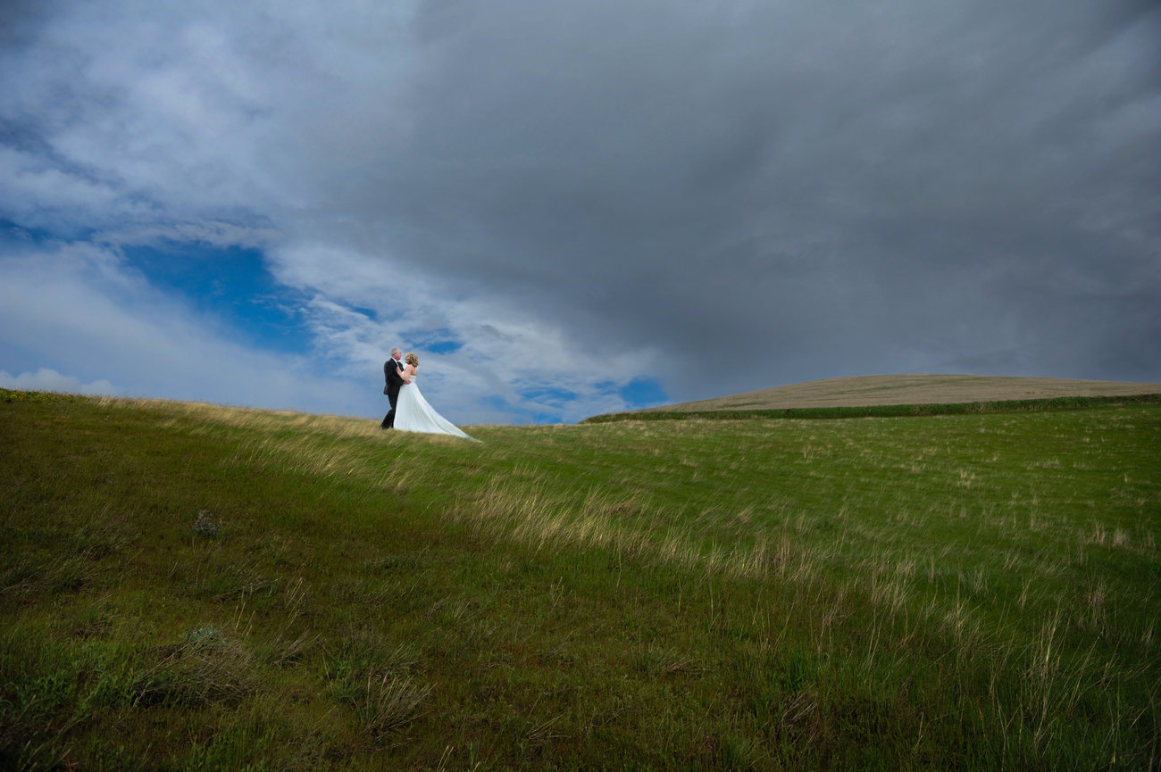 Person walking across a grassy ridge under a dramatic cloudy sky.