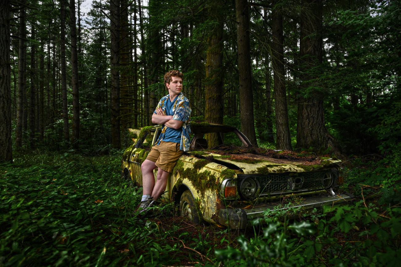 Woman sitting on a moss-covered bench in a forest.