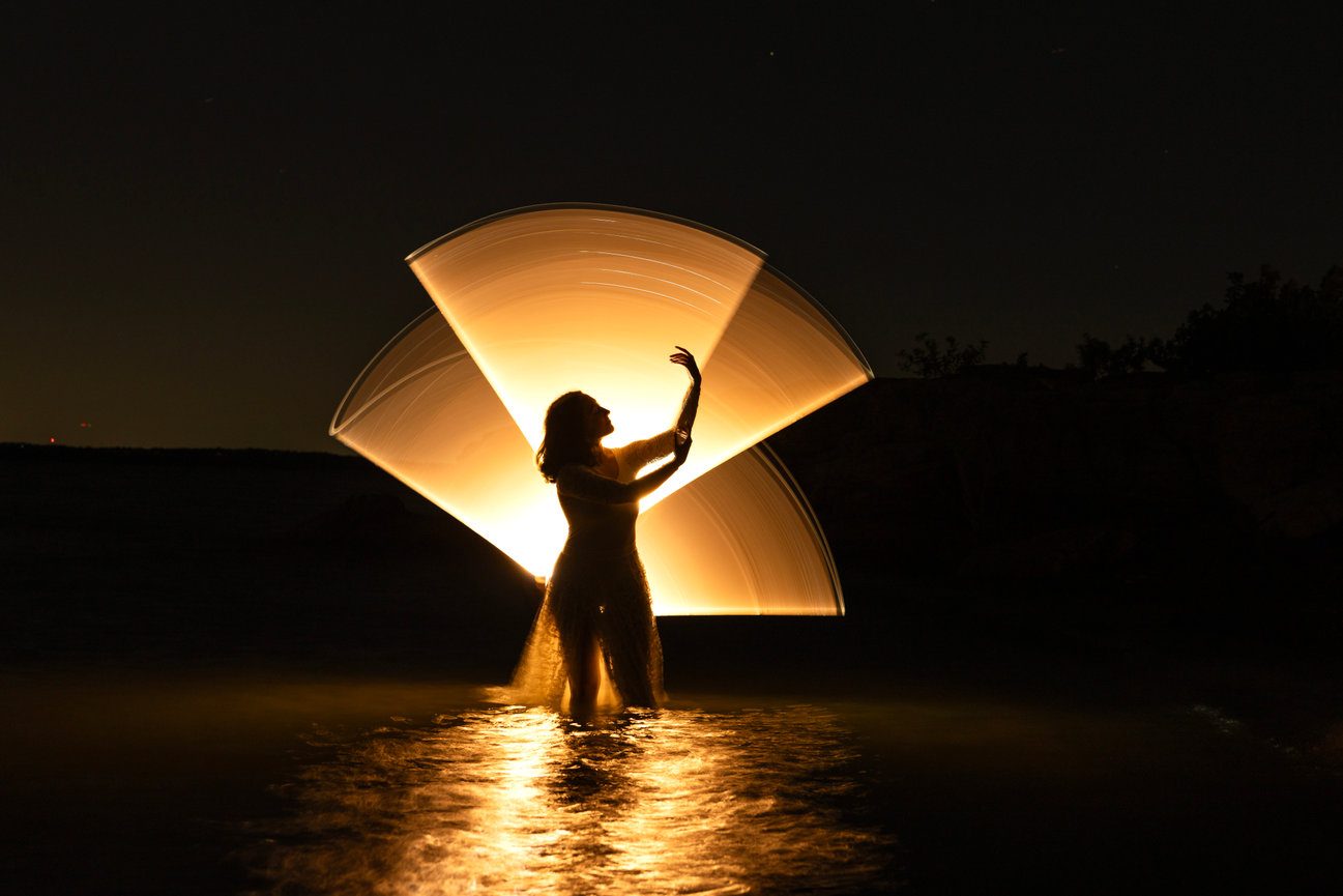 Light painting portrait in water with glowing orange fan effect, DFW creative portrait photographer