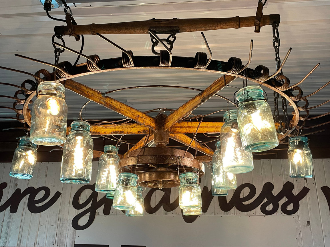 A rustic chandelier made from a repurposed farm rake wheel and vintage mason jars.
