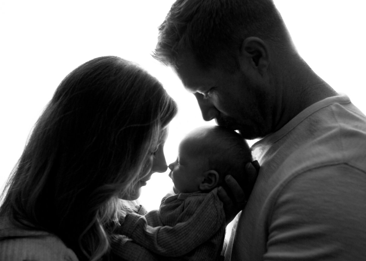 Close up profile black and white image of a mother and father holding their newborn baby during photoshoot with Kansas City newborn photographer Dreamworks Photography