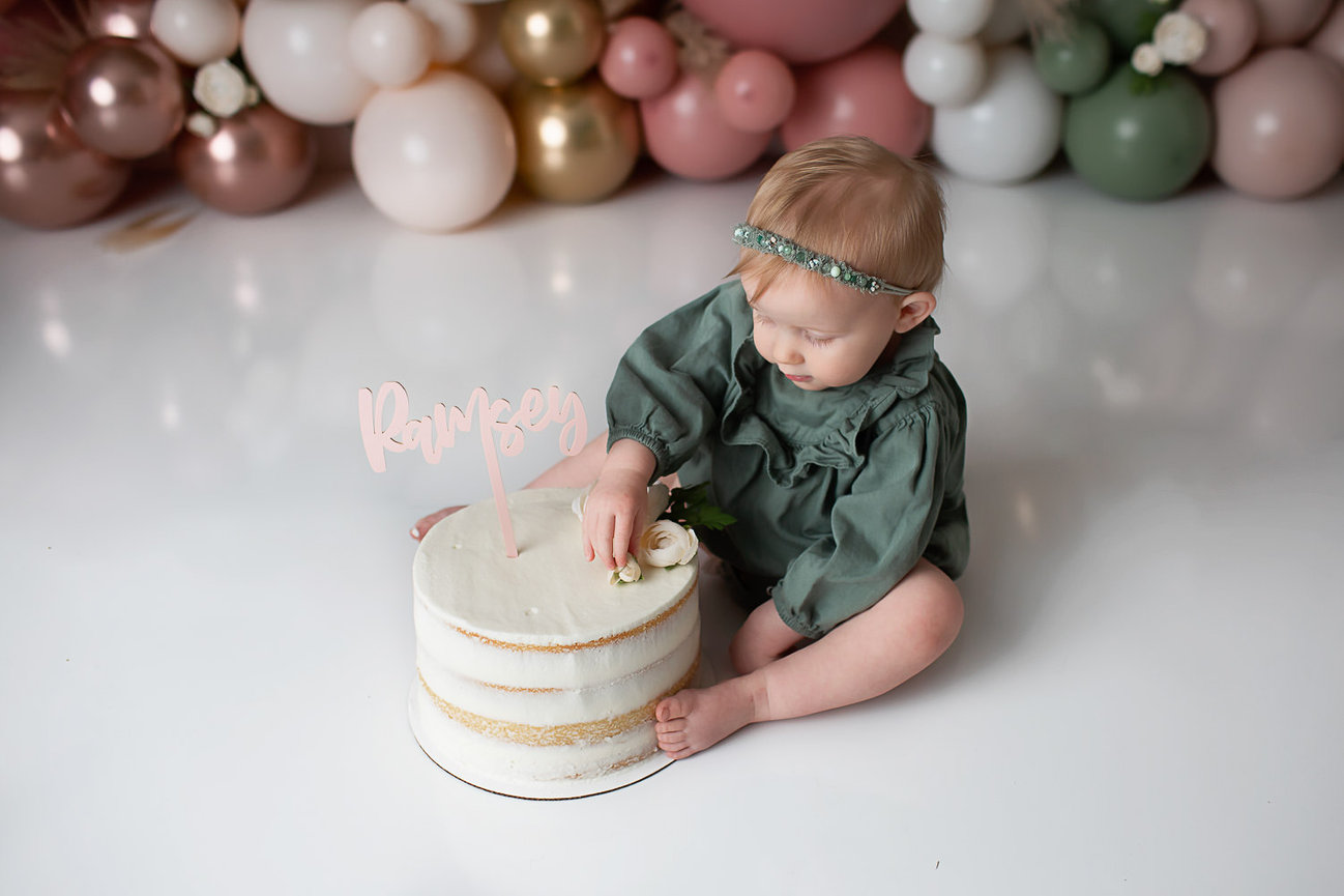 baby girl eating cake during cake smash photoshoot with newborn baby photographer Dreamworks Photography in Kansas City