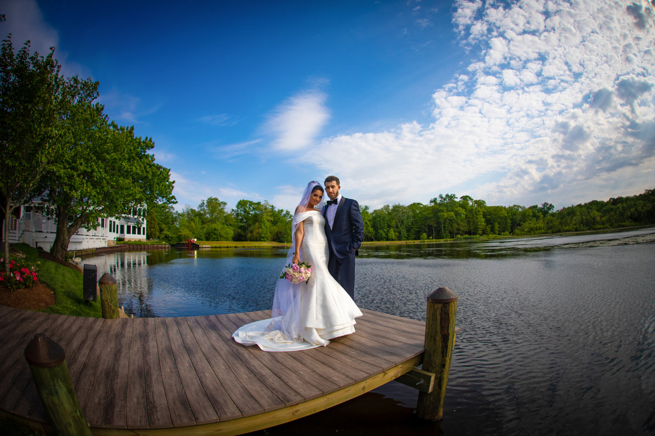 Bride and groom on a wooden dock beside a lake at sunset