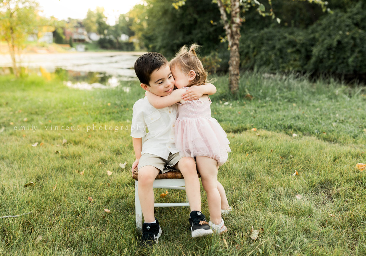 Siblings hugging and laughing together during outdoor family session
