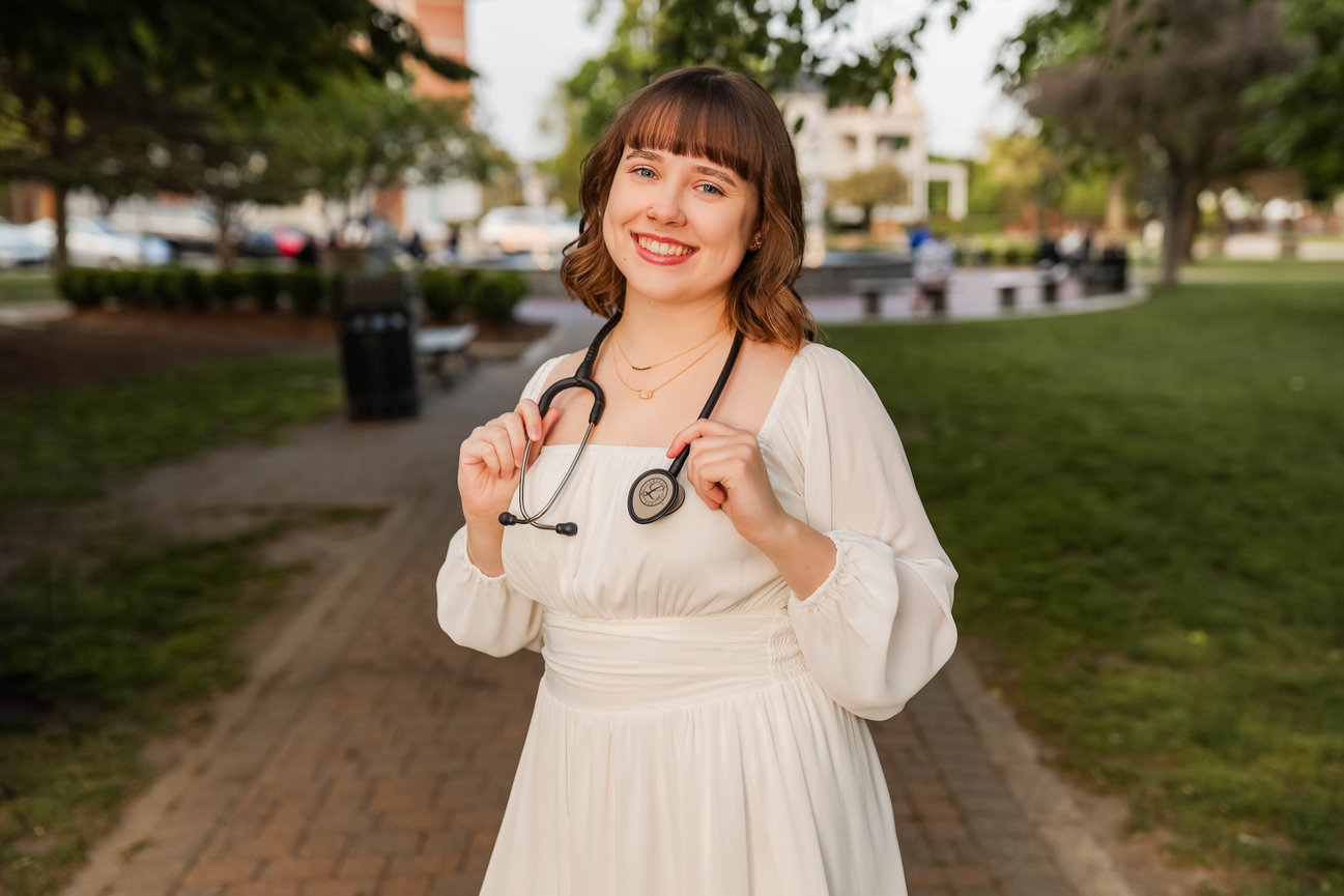 Outdoor business headshot of woman with stethoscope and fountain, city background