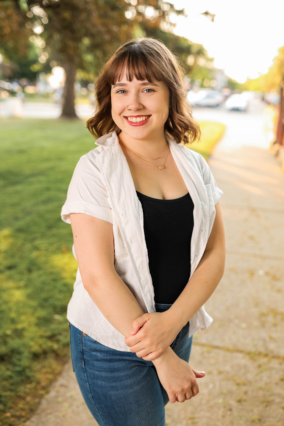 Outdoor business headshot of professional woman with tree and greenery in background