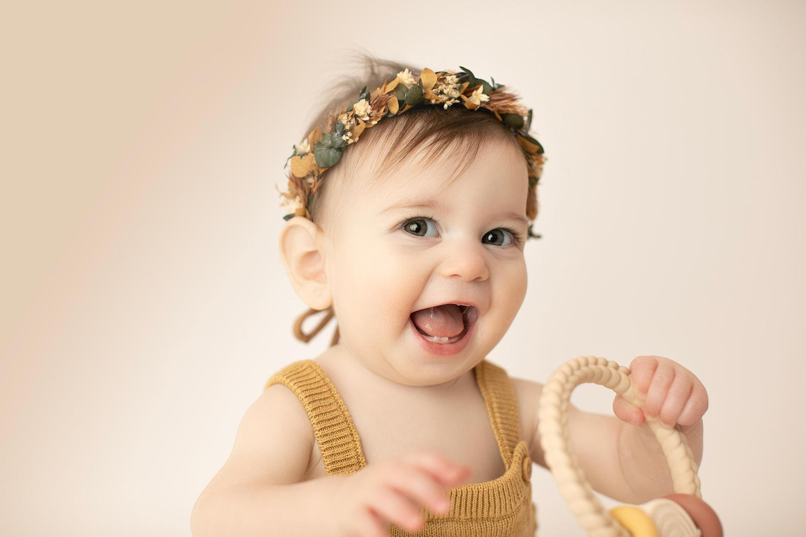 Baby laughing in a mustard outfit and floral headband
