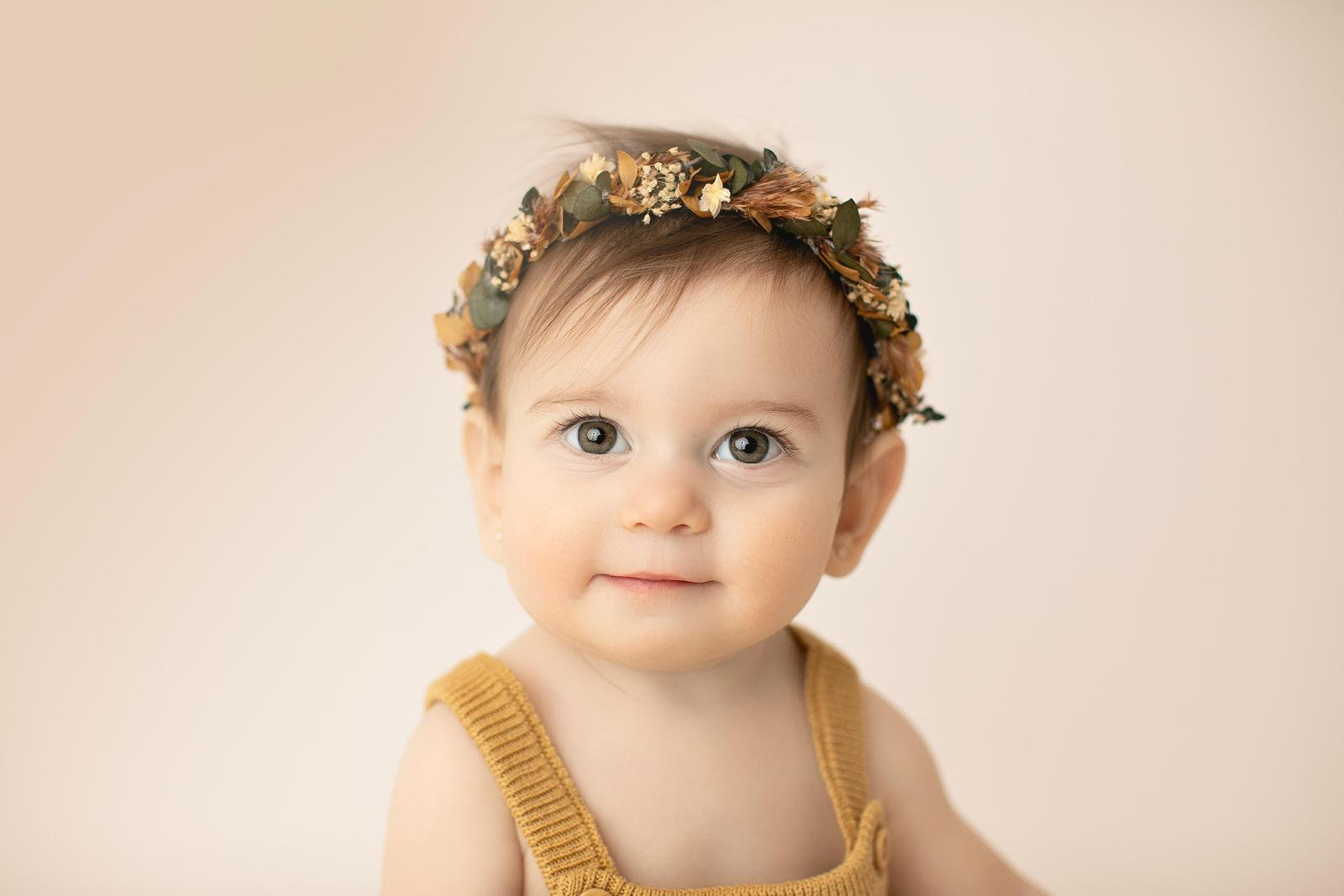 Baby looking towards the camera in a mustard outfit