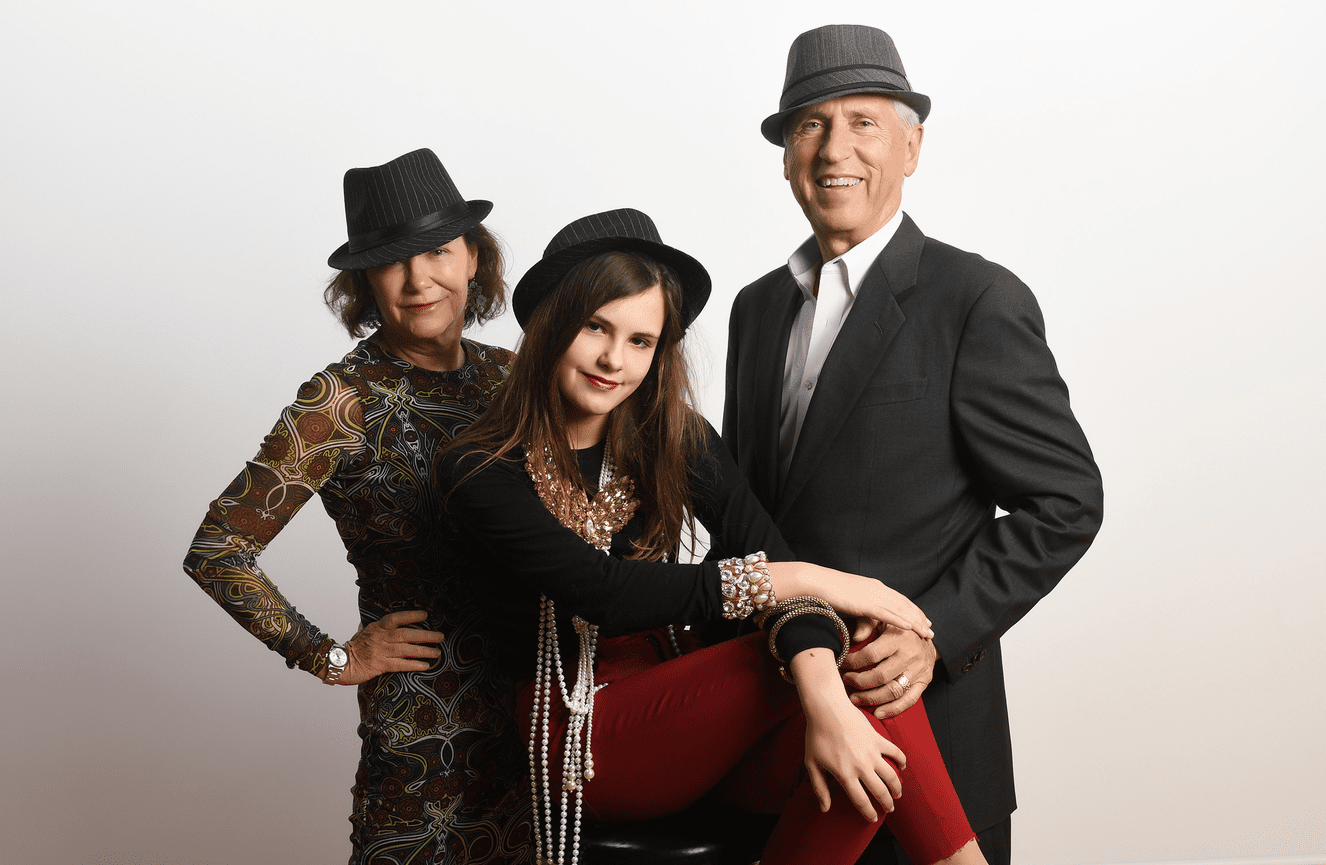 A grandmother and grandfather in fedora hats and layers of pearls and faux diamonds at Kliks Photography.
