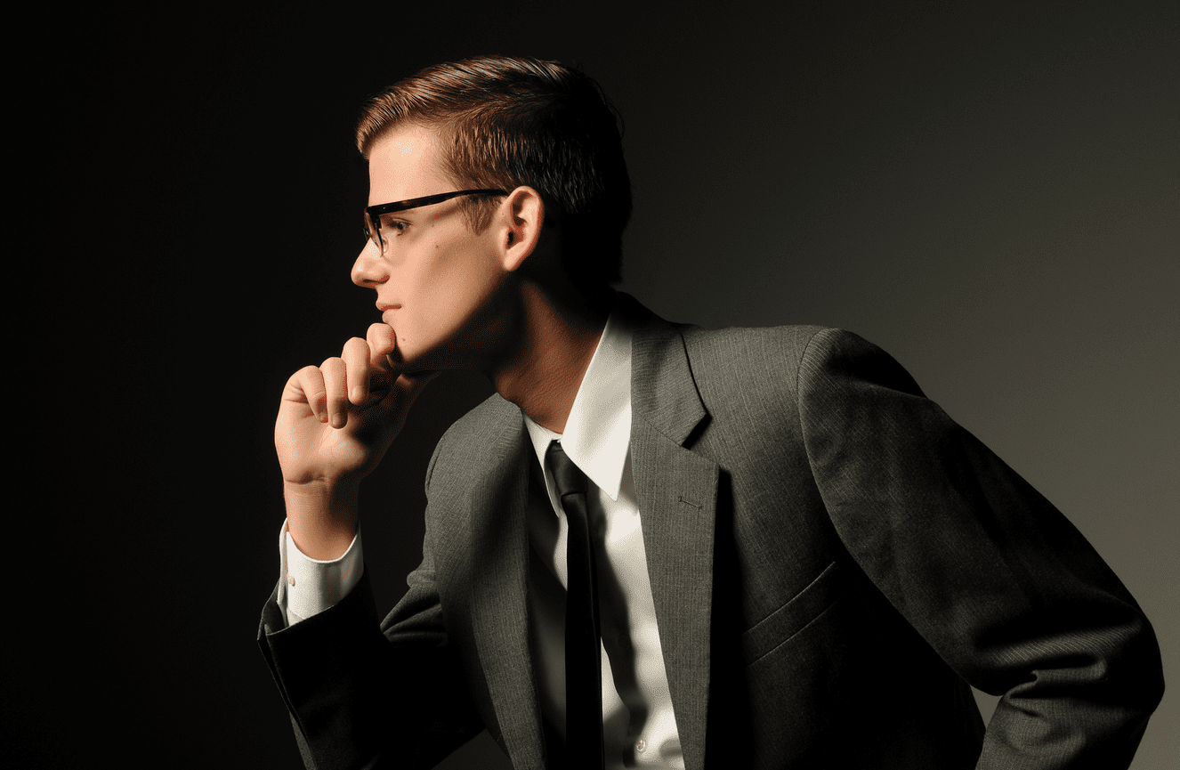 A profile of a young man in a suit and tie.