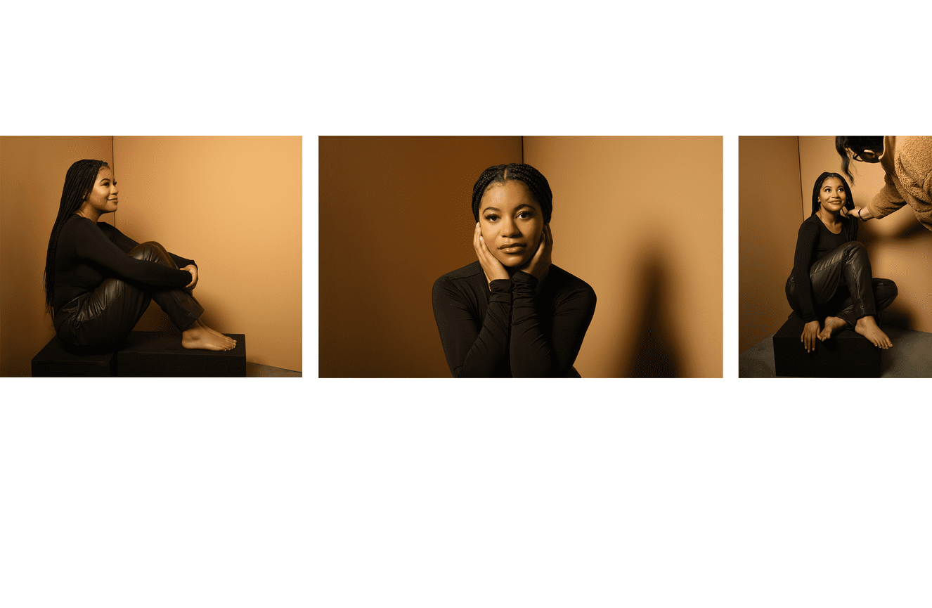 An African American teenage poses in front of a mustard background for her senior photos.