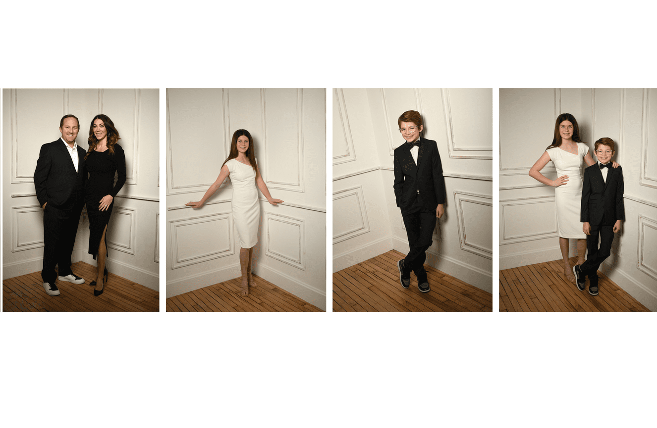 A family of four dressed in formal black suits and white cocktail dresses.