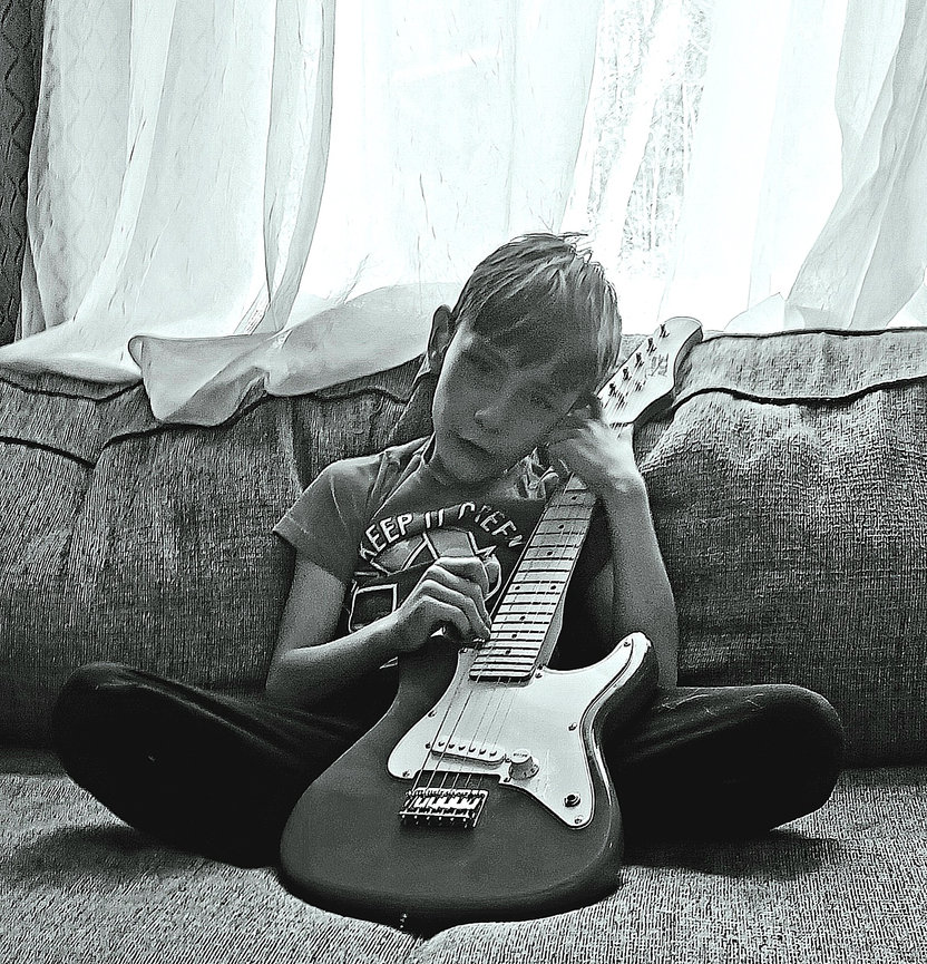 Black and white image of a child sitting with a guitar