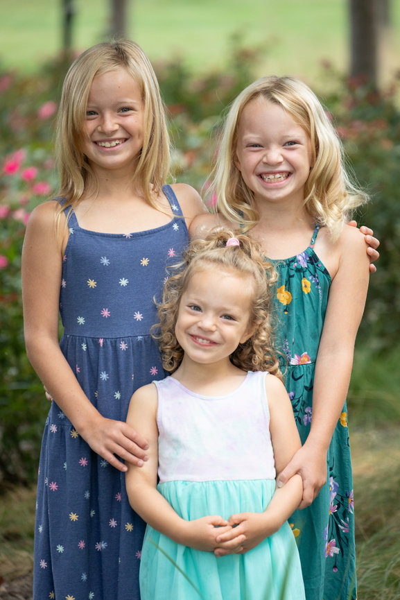 Three young girls posing in a garden