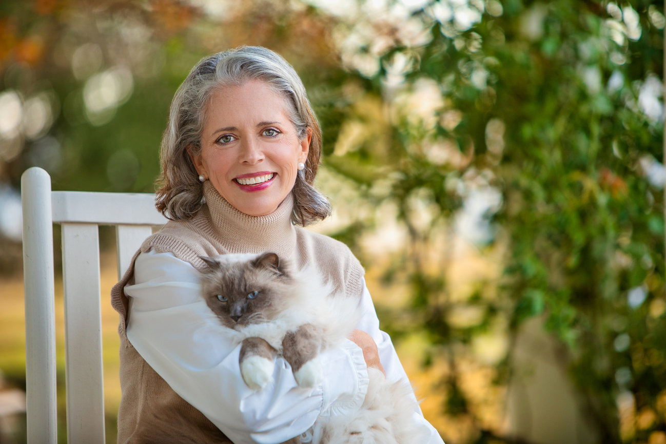 Portrait of a woman with her persion cat sitting in a rocking chair.