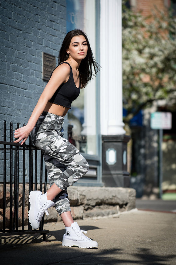 Dark haired teenage girl in workout clothes posing for senior pictures in Dublin OH.