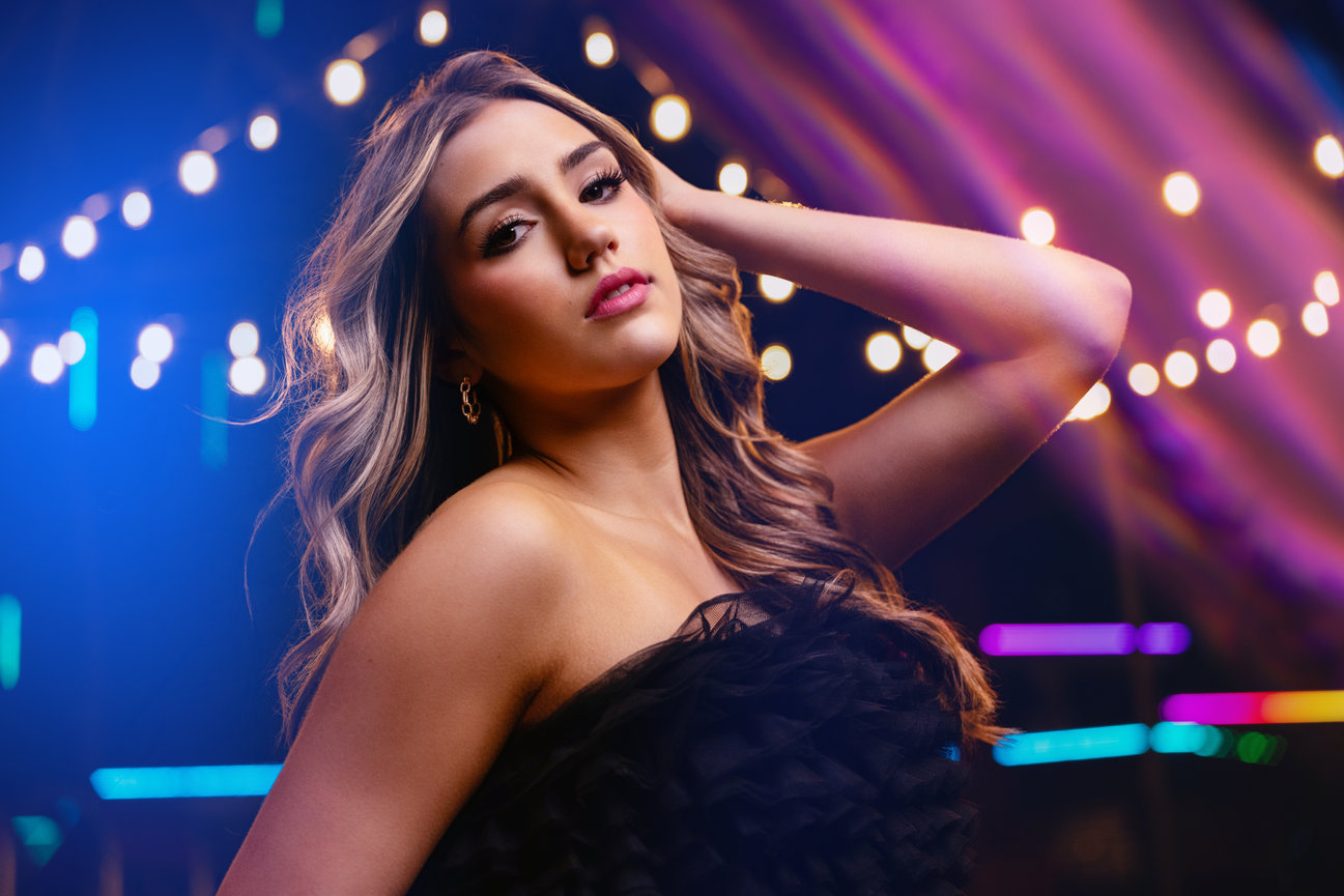 Woman posing under colorful neon lights in a nightlife setting.
